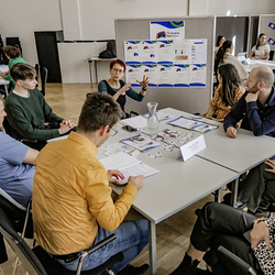 Monika Gigerl präsentiert im Rahmen des Slow-Datings das Projekt „European Heart“ einer interessierten Gesprächsgruppe. Auf dem Tisch liegen Projektmaterialien.