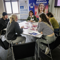 Susanne Feirer spricht im Rahmen des Slow-Dating-Formats mit jungen Teilnehmenden über Gleichbehandlung im Berufsleben. Infomaterial liegt auf dem Tisch.