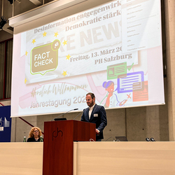Begrüßungsworte Maximilian Müller von der Europäischen Kommission am Podium, im Hintergrund Leinwand auf der Jahrestagung angekündigt wird.