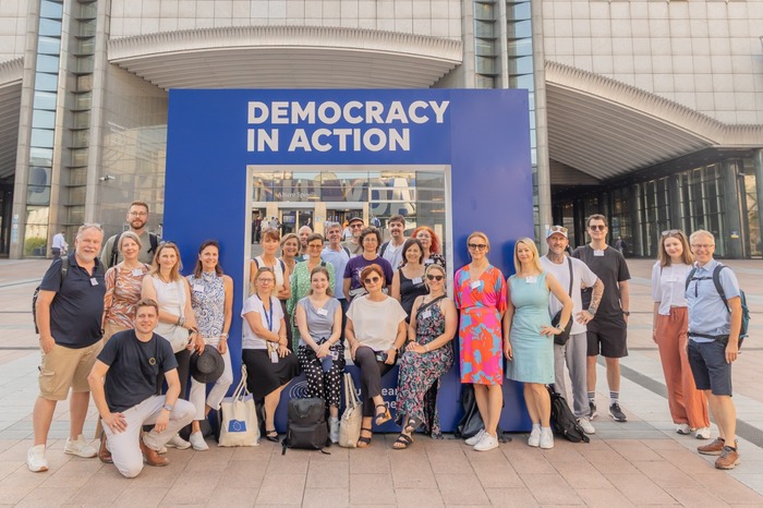 Gruppe Bildungsreise nach Brüssel / Wolfgang Lackner Gruppenbild vor dem Schild 'Democracy in Action'