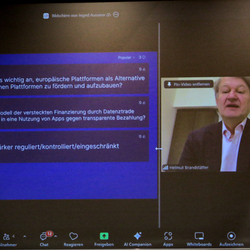 Auf der Videowall ist Europabgeordneter Helmut Brandstätter und eingeblendete Frage mit dem Umfragetool Slido zu sehen